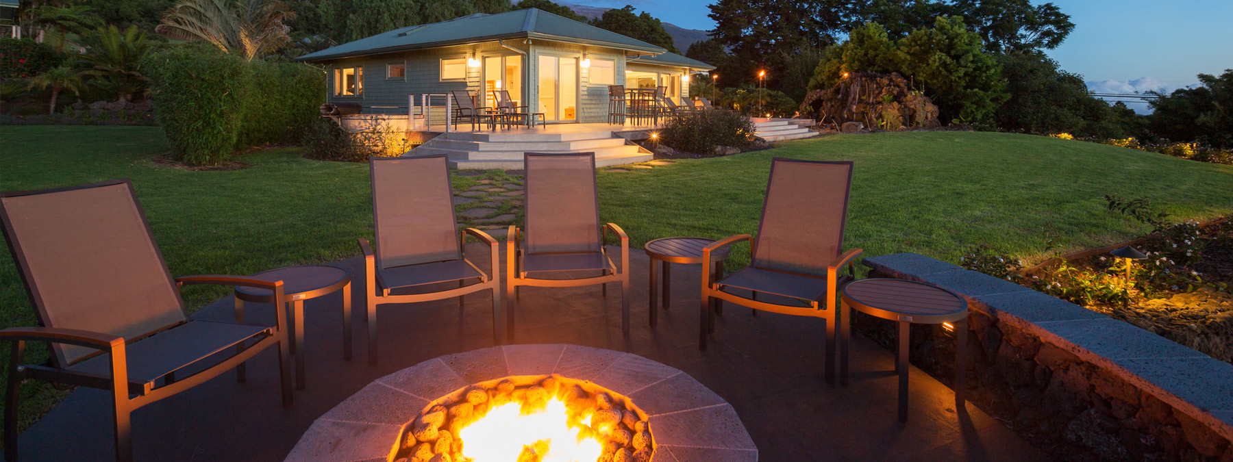 A fire pit with chairs around it in the evening.
