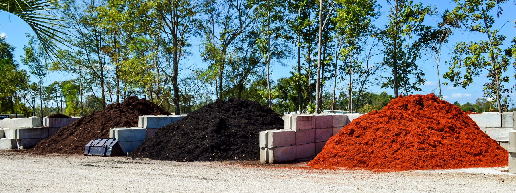 A pile of mulch and bricks in front of some trees.